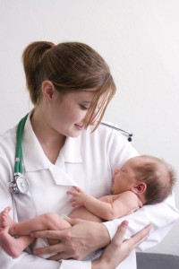 Smiling young doctor holding a beautiful newborn baby.